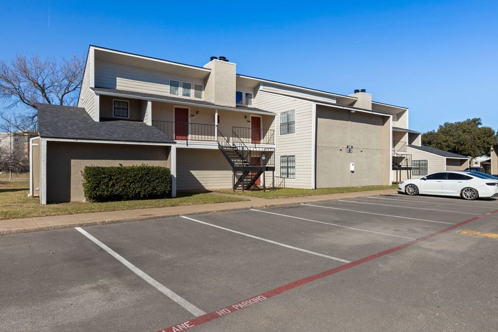 A white car is parked in a parking lot in front of a building.