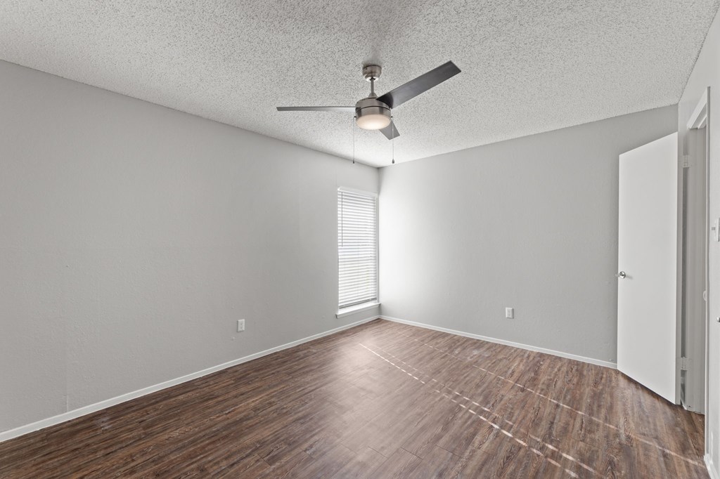 A room with a ceiling fan and wooden flooring.