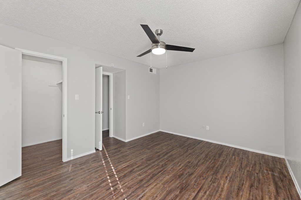 A room with a ceiling fan and wooden flooring.