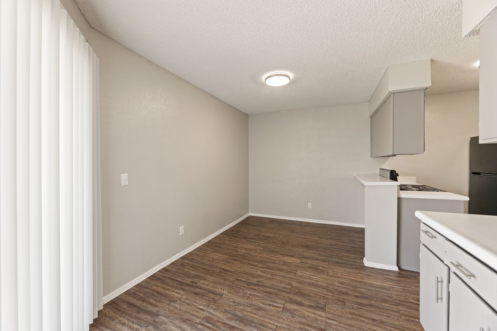 A kitchen area with white cabinets and a wooden floor.
