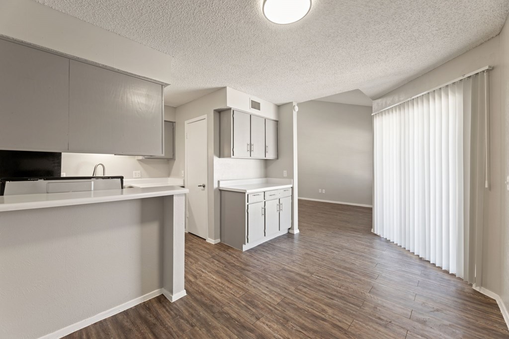 A kitchen with white cabinets and a wooden floor.