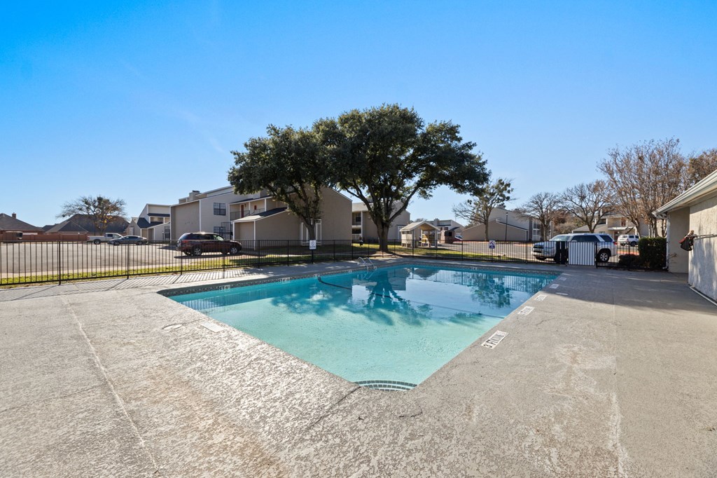 A swimming pool in a residential area surrounded by houses and trees.
