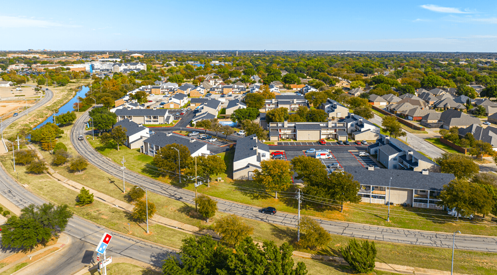 A road with a traffic light and a parking lot.