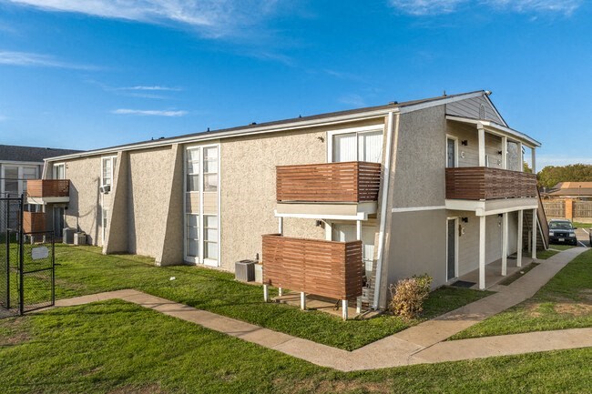 an apartment building with a porch and a green lawn
