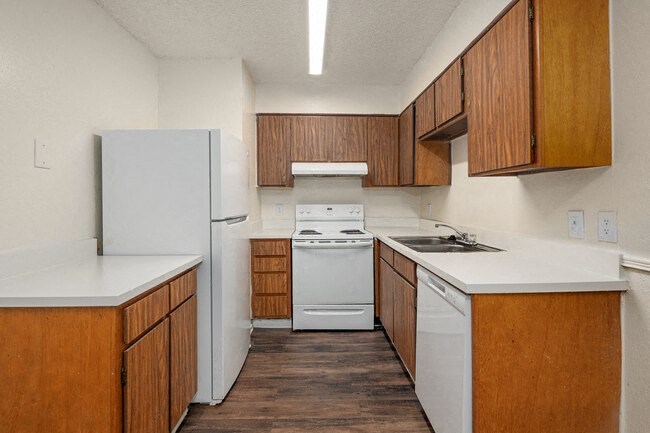 an empty kitchen with white appliances and wooden cabinets