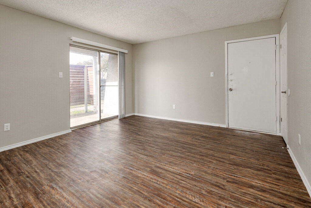 an empty living room with wood floors and a sliding glass door