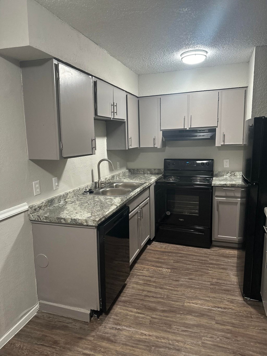 a kitchen with white cabinets and black appliances