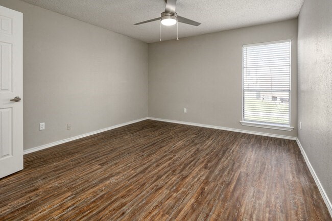 an empty living room with wooden floors and a ceiling fan