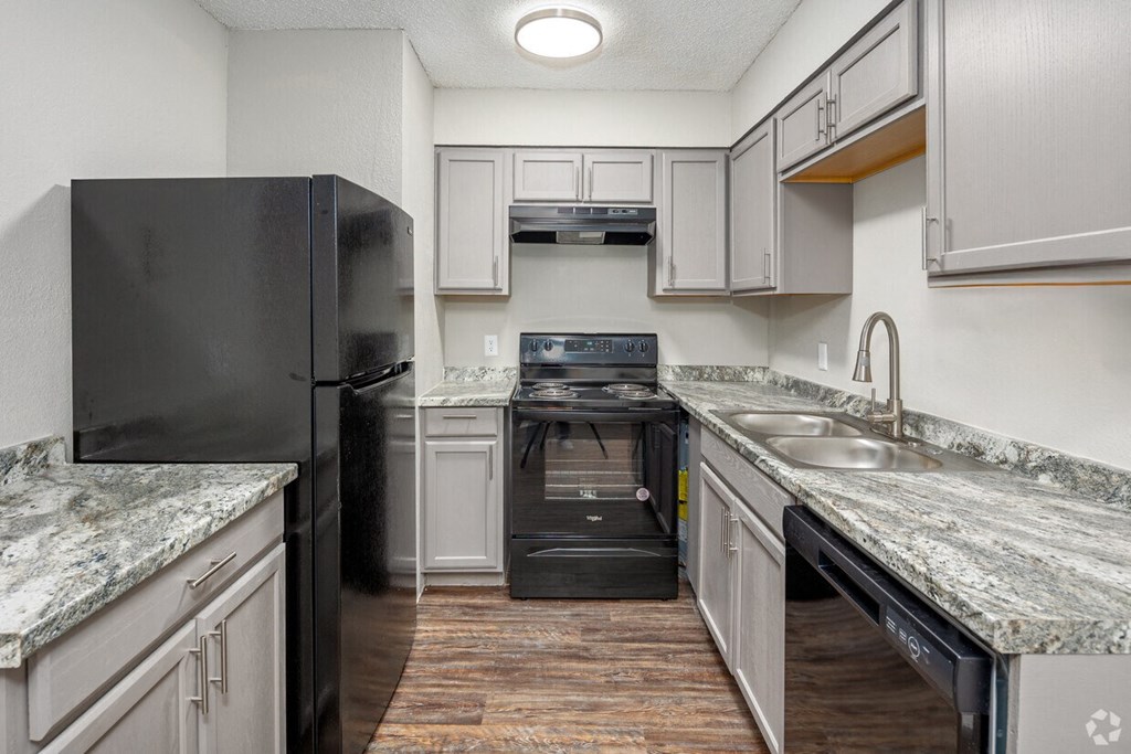 a kitchen with white cabinets and black appliances and granite counter tops