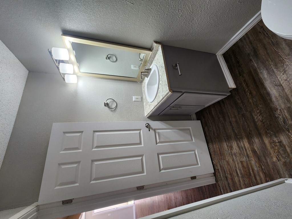 A white door is open to a small bathroom with a toilet and a cabinet.