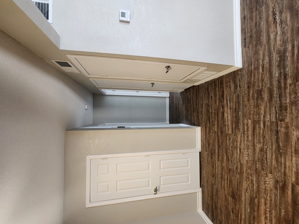 A white cabinet with a drawer is under a vent in a room with a brown wall.