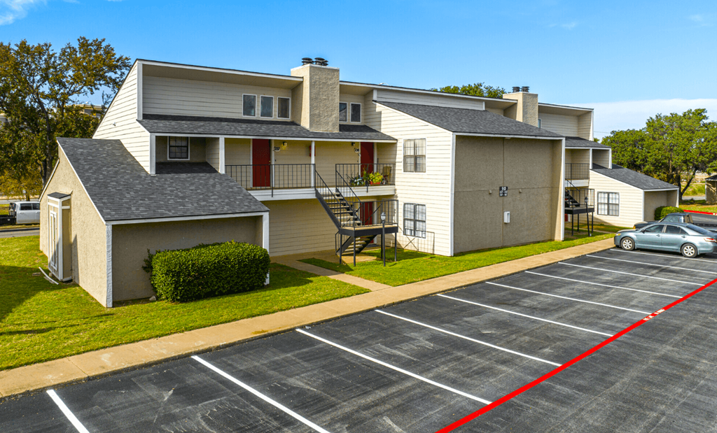 A parking lot in front of a two-story apartment building.