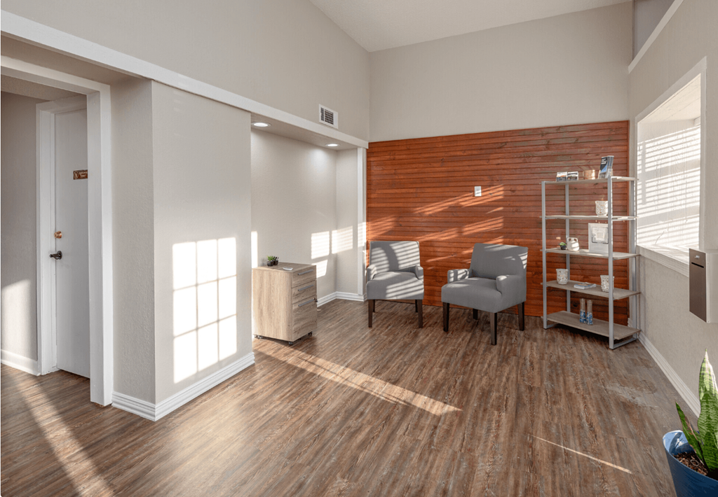 A room with a wooden floor and a wooden wall with a chair and a table in it.
