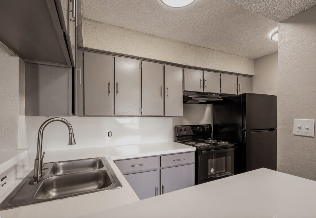 A kitchen with a stainless steel sink and white countertop.