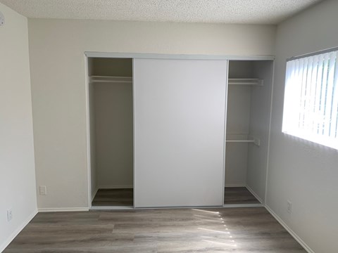 an empty bedroom with a closet and a window