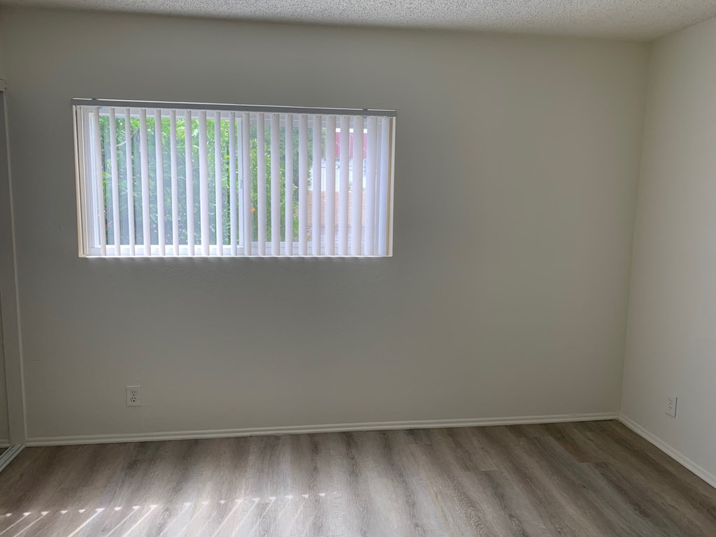 an empty room with wood floors and a window