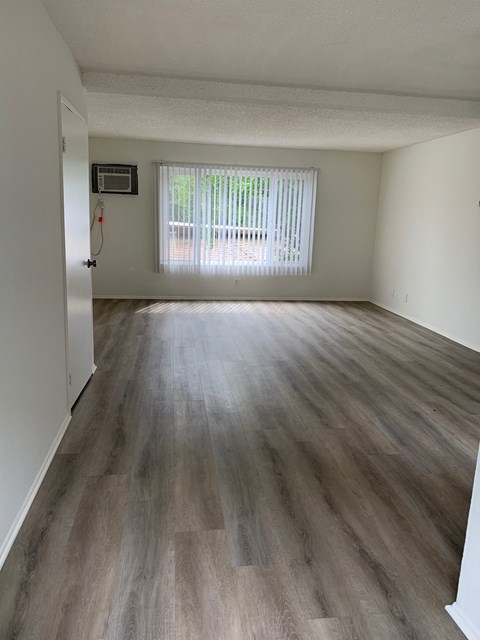 an empty living room with wood flooring and a window