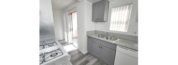 A kitchen with a stove, sink, and cabinets.