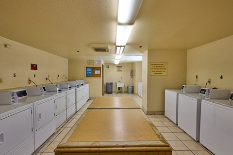 A laundromat with washers and dryers lined up on both sides of a central aisle.