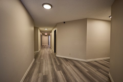 A long hallway with wood flooring and white walls.