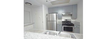 A kitchen with a stainless steel refrigerator, oven, and sink.