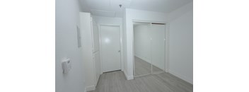 A white door is in a room with a white wall and a light switch.