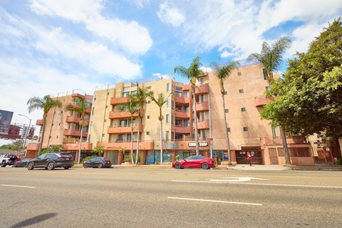 A red car is parked on the side of the road in front of a building.