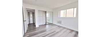 A spacious room with a wood floor and a wall of windows.