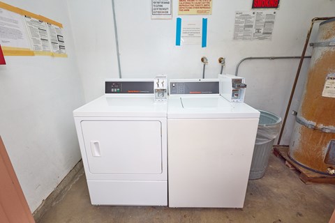 A white appliance with a black top sits in a room with a warning sign on the wall.