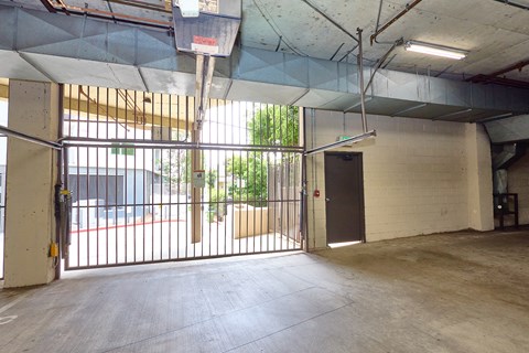 A large, empty garage with a basketball hoop and a basketball on the ground.