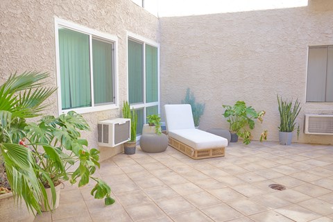 A patio with a white chair, a table, and a potted plant.