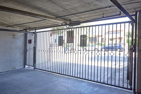 A black gate with a diamond pattern leads to a parking lot.