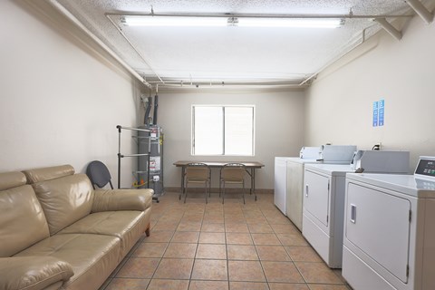 A room with a tan couch, a table, and a washing machine.