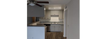 A kitchen with white cabinets and a fan on the ceiling.