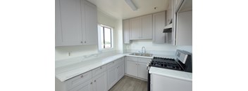 A kitchen with white cabinets and a black stove top.