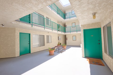 A balcony with green railings is on the second floor of a building.
