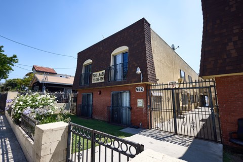 A brick building with a gate and a sign that says "FOR LEASE".