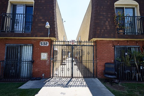 A black gate with the number 622 on it is in front of a brick building.