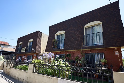 A red brick building with a black iron fence in front.