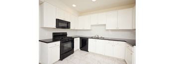 A kitchen with black and white appliances and cabinets.