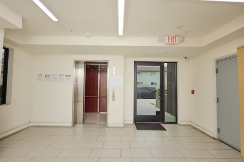 A white hallway with a red exit sign above the door.