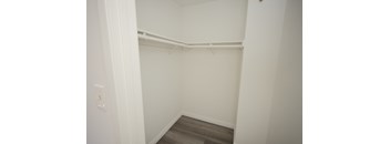 A white closet with a wooden floor and a white door.