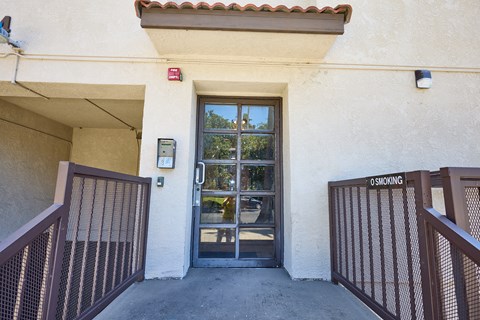 A building entrance with a glass door and a sign that says "No Smoking".