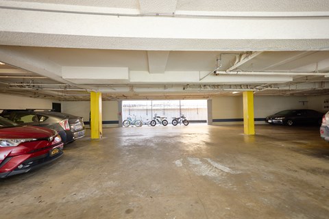 A parking garage with a red car on the left and a black car on the right.