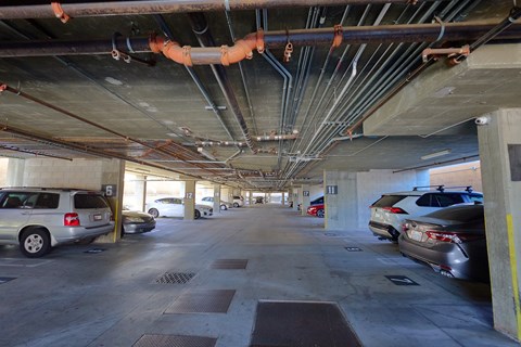 A parking garage with cars parked on the ground floor.