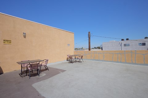 A patio with a table and chairs is in front of a tan wall.