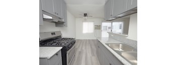 A kitchen with a stove, sink, and cabinets.
