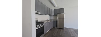 A kitchen with a stove, sink, and refrigerator.