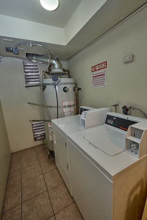 A washing machine in a laundry room with a warning sign on the wall.