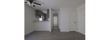 A room with a ceiling fan and a long hallway.